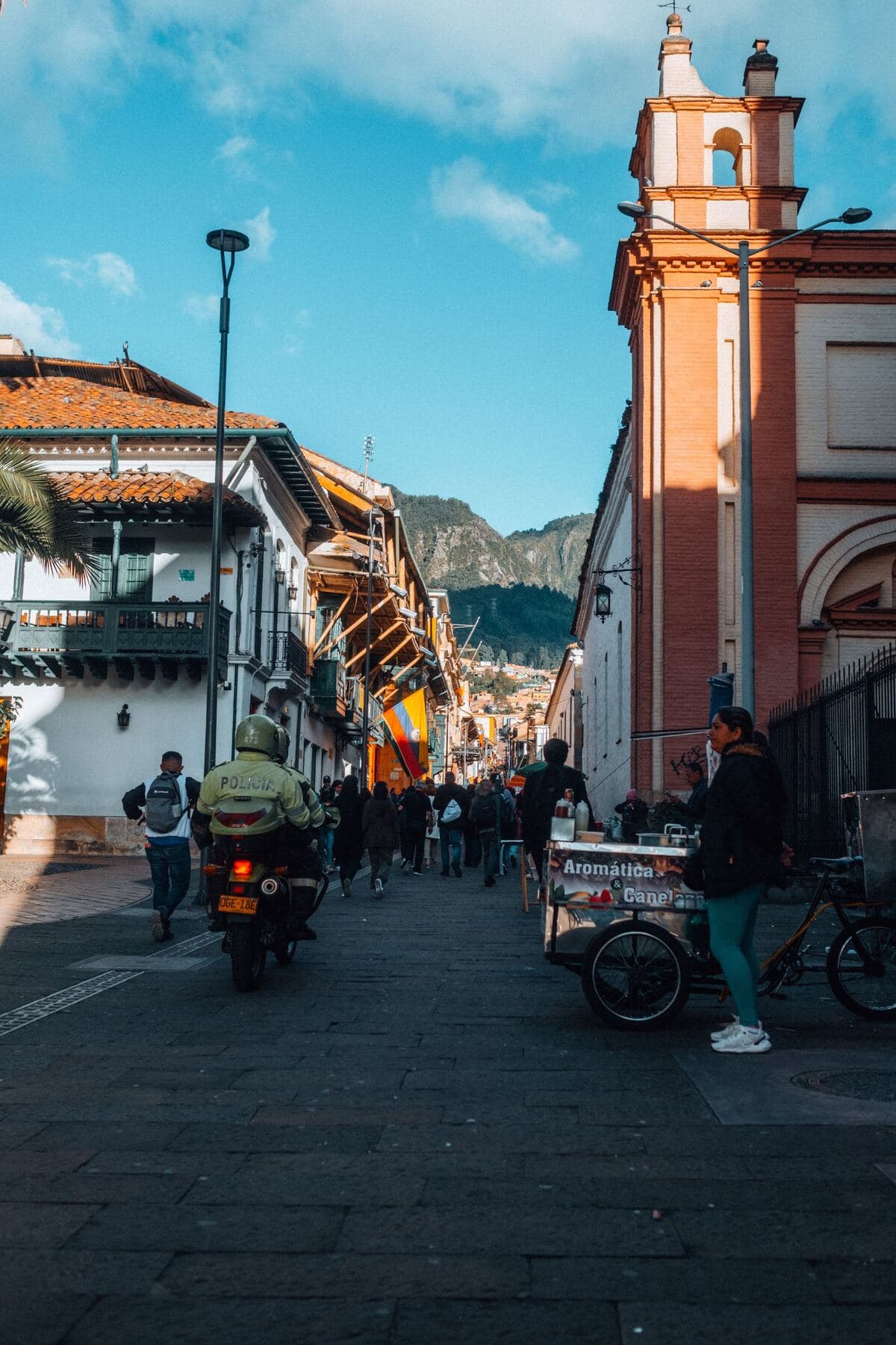 Una calle comercial de Bogotá a media tarde, con gente caminando.