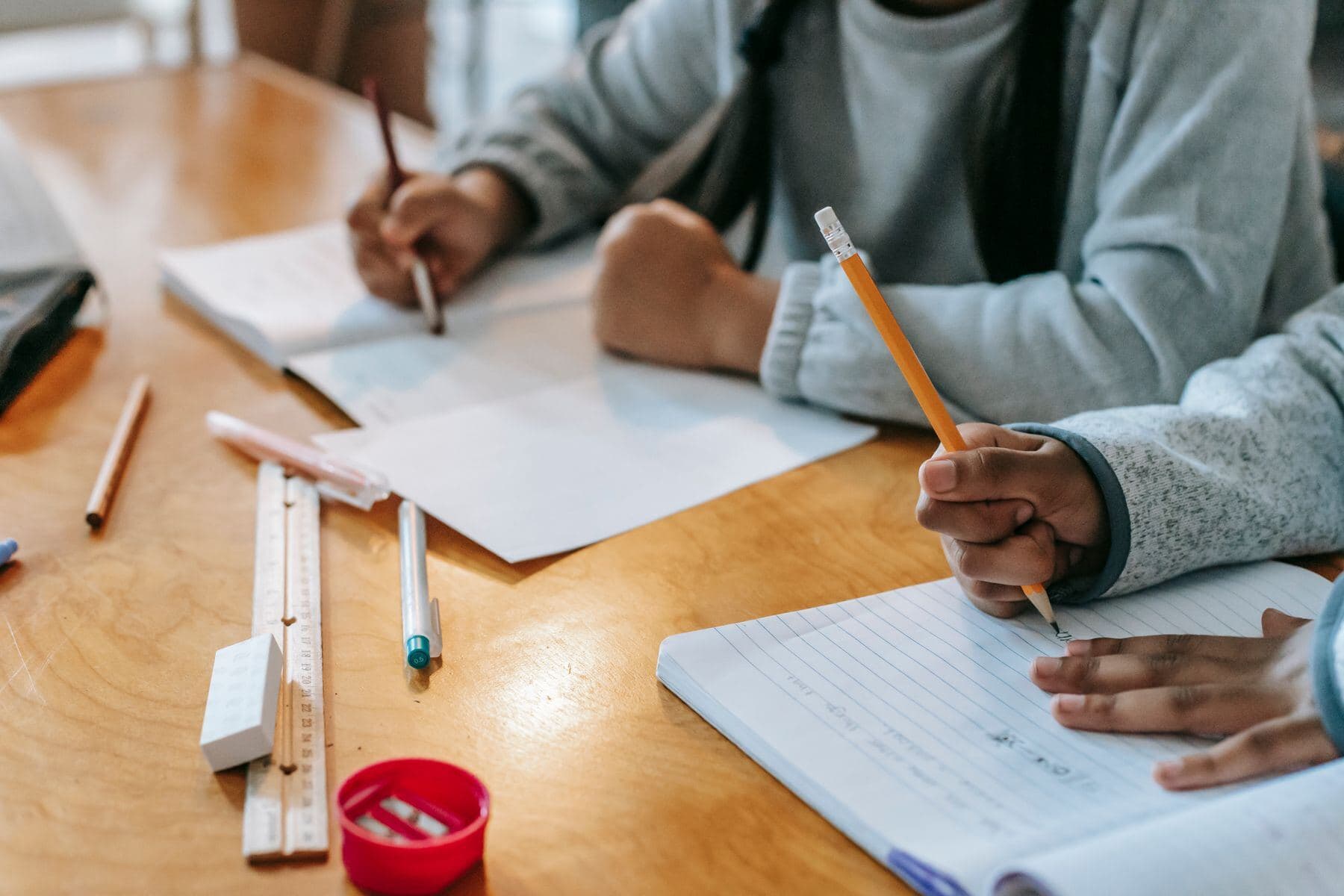 Two students writing in their notebooks at a table.